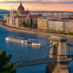 A photo of an aerial view of a river cruise ship moving along a river bank