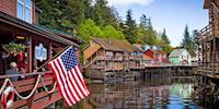 Waterfront buildings in Ketchikan, with an American flag hanging over the water.