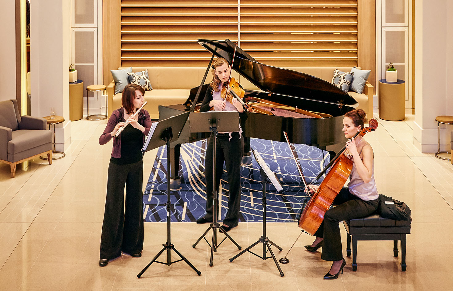 Three women performing music in front of a piano